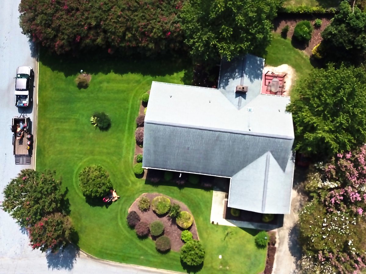 A home from above with fresh mowing lines and mulched beds.